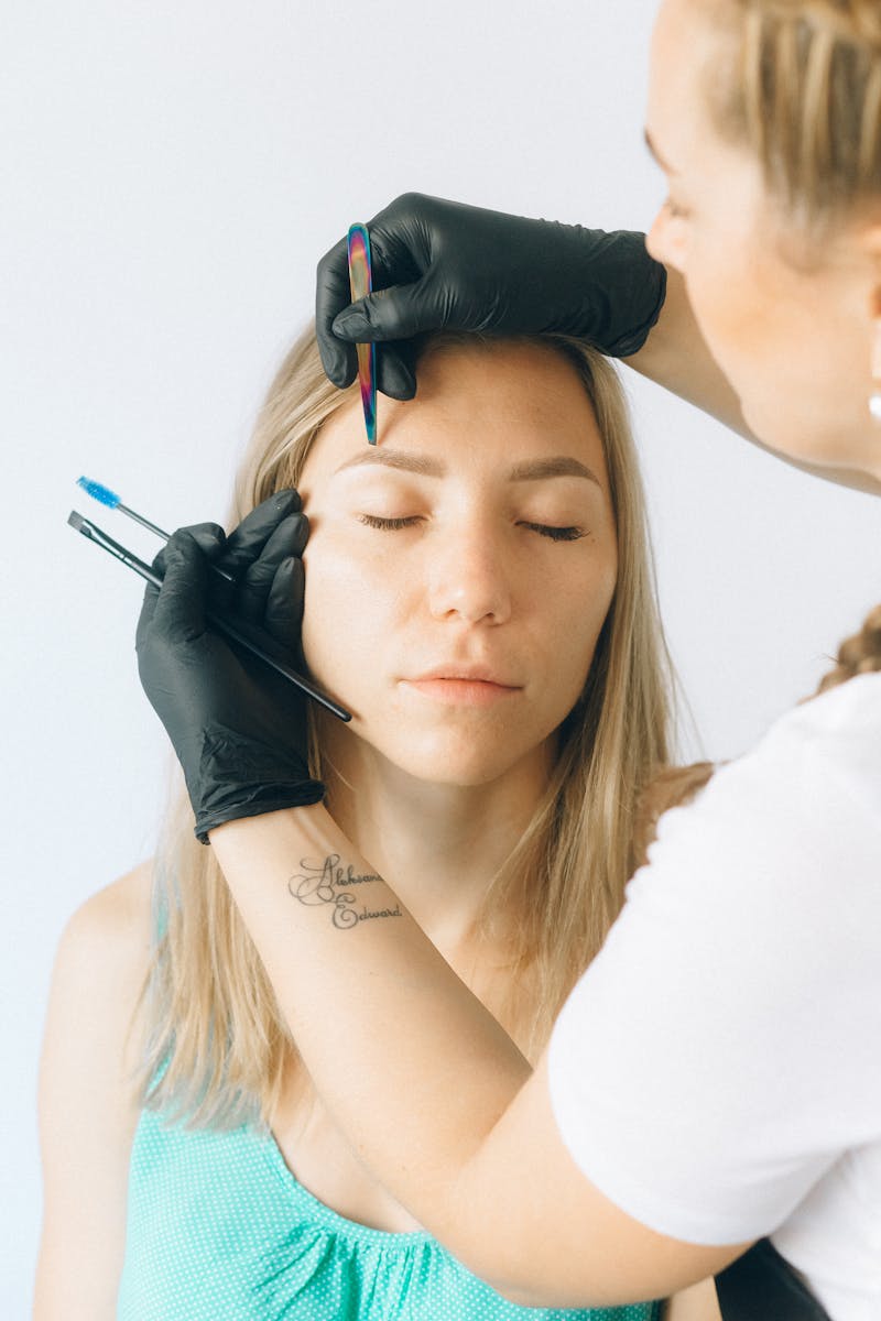 Professional eyebrow shaping and microblading session captured indoors.